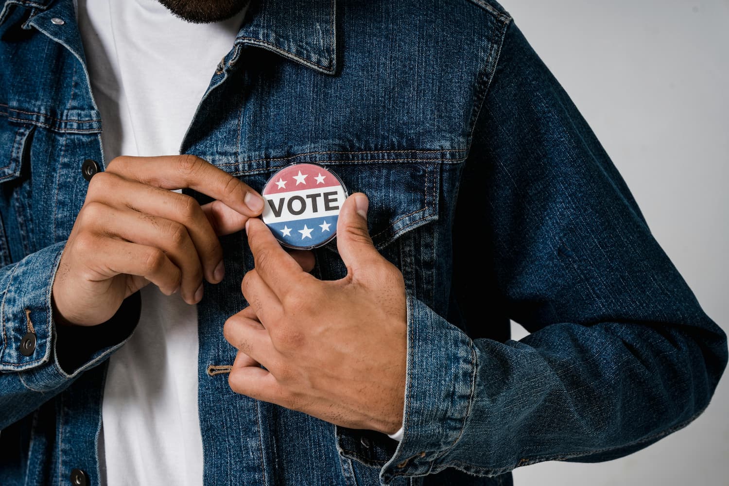 Man wearing a denim jack with a button that says 